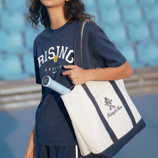 AROSRIS Heritage Canvas Tote styled with athletic outfit — showing court-to-city versatility and shoulder carry
