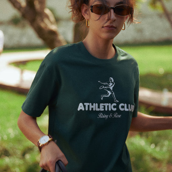 AROSRIS Kay Stammers Tribute Tee in Varsity Green — outdoor lifestyle shot showing premium Xinjiang cotton drape and graphic detail