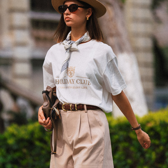 AROSRIS Princess High-Waist Tailored Pleated Shorts in Beige — full body lifestyle shot showing A-line silhouette styled with white top and straw hat