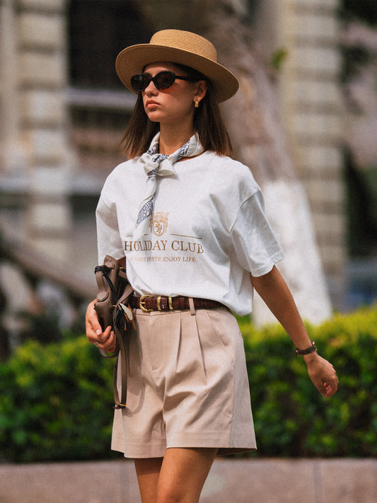 AROSRIS Princess High-Waist Tailored Pleated Shorts in Beige — full body lifestyle shot showing A-line silhouette styled with white top and straw hat