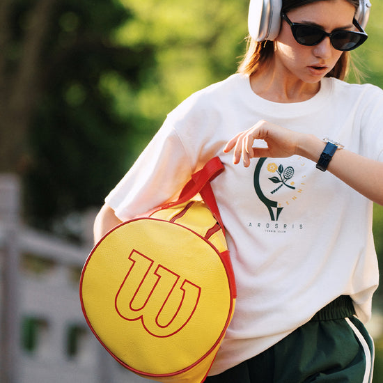 AROSRIS Morning Run Waffle Knit Graphic Tee in white — model with tennis racket bag, sporty street style