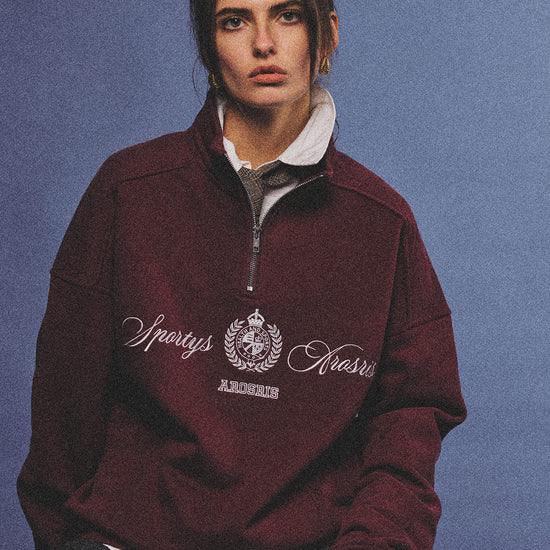 Arosris burgundy vintage-inspired campus half-zip sweatshirt with a custom crest embroidery, styled with biker shorts and retro sneakers for an effortless 90s sporty-chic aesthetic.