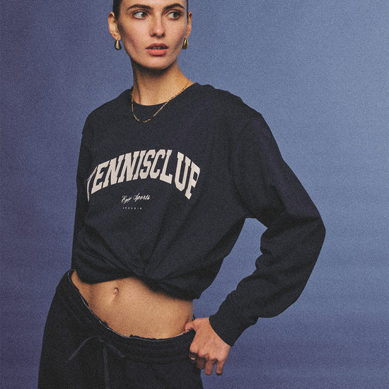 Arosris navy campus long sleeve t-shirt crafted from premium Pima cotton, featuring a vintage 'TENNISCLUB' graphic, elegantly styled with layered activewear for an effortless 90s sporty-chic aesthetic.