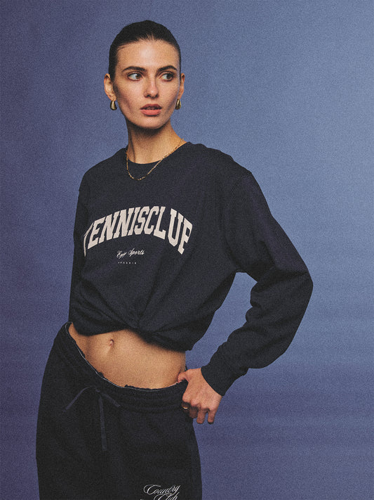 Arosris navy campus long sleeve t-shirt crafted from premium Pima cotton, featuring a vintage 'TENNISCLUB' graphic, elegantly styled with layered activewear for an effortless 90s sporty-chic aesthetic.