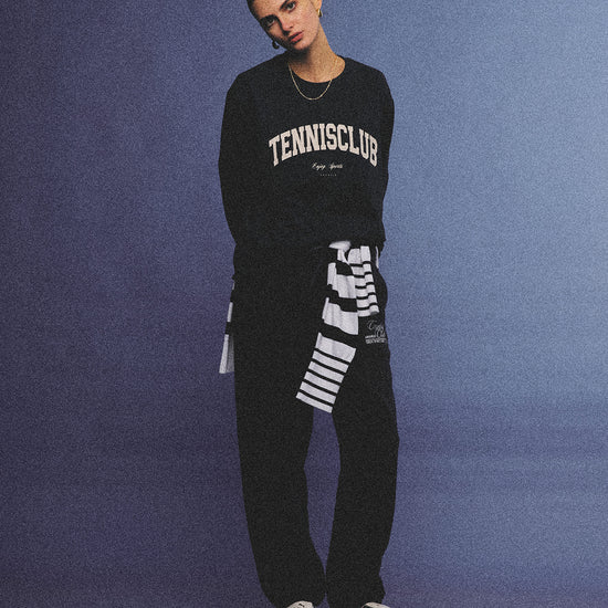 Arosris navy campus long sleeve t-shirt crafted from premium Pima cotton, featuring a vintage 'TENNISCLUB' graphic, elegantly styled with layered activewear for an effortless 90s sporty-chic aesthetic.