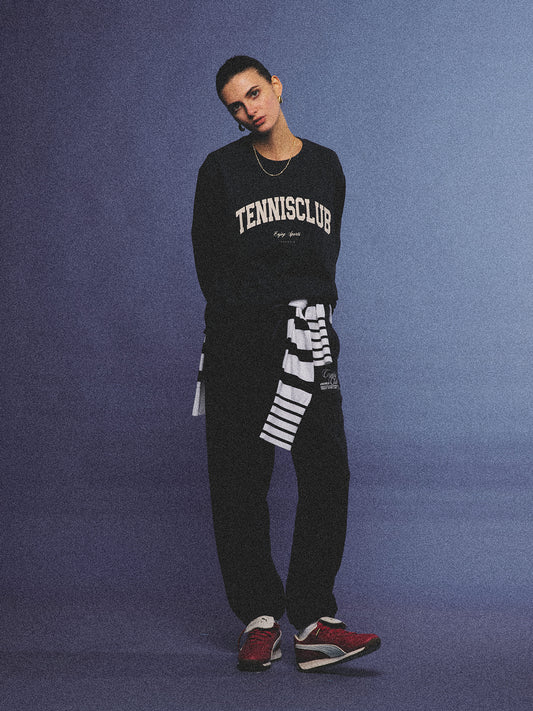 Arosris navy campus long sleeve t-shirt crafted from premium Pima cotton, featuring a vintage 'TENNISCLUB' graphic, elegantly styled with layered activewear for an effortless 90s sporty-chic aesthetic.
