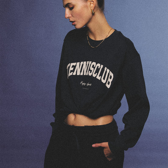 Arosris navy campus long sleeve t-shirt crafted from premium Pima cotton, featuring a vintage 'TENNISCLUB' graphic, elegantly styled with layered activewear for an effortless 90s sporty-chic aesthetic.