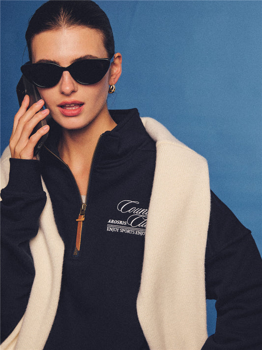 Arosris navy country club half-zip sweatshirt, expertly layered with a classic trench coat and vintage accessories for an effortless 90s sporty-rich aesthetic.