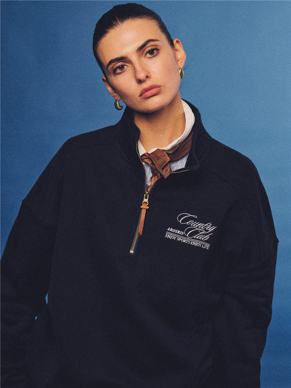 Arosris navy country club half-zip sweatshirt, expertly layered with a classic trench coat and vintage accessories for an effortless 90s sporty-rich aesthetic.