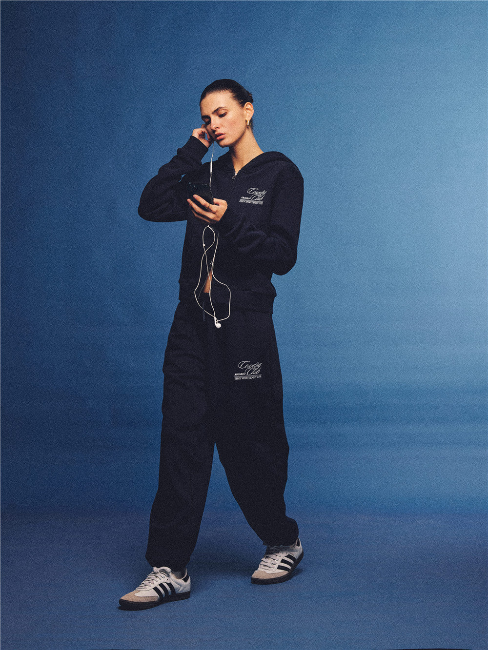 Arosris navy country club slim zip hoodie, styled with matching sweatpants and retro sneakers for an effortless 90s off-duty sporty-chic aesthetic.