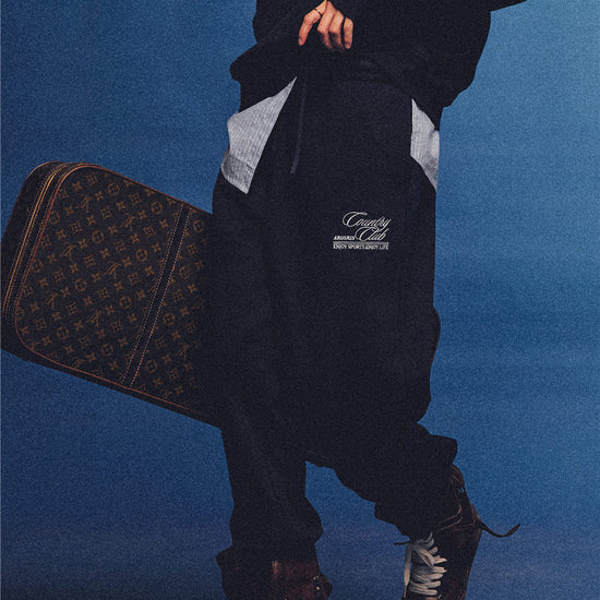 Arosris navy country club relaxed sweatpants, styled with a classic trench coat and vintage accessories for an effortless 90s sporty-rich aesthetic.