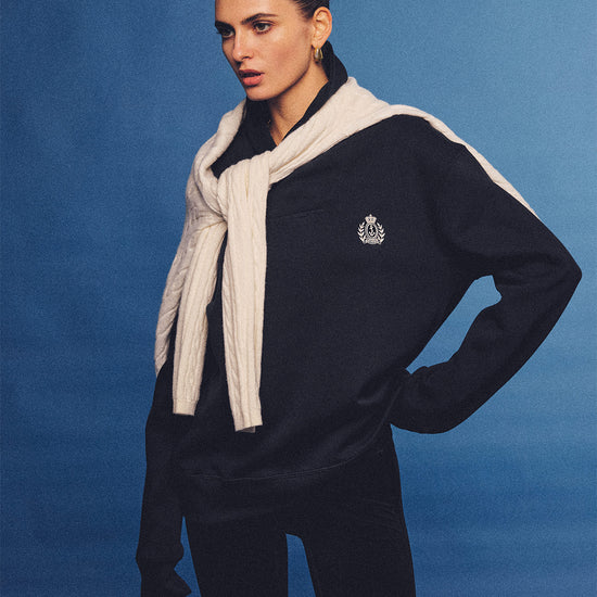 Arosris navy offshore crest shawl collar sweatshirt, styled with a tied sweater and retro sneakers for an effortless 90s vintage country club aesthetic.