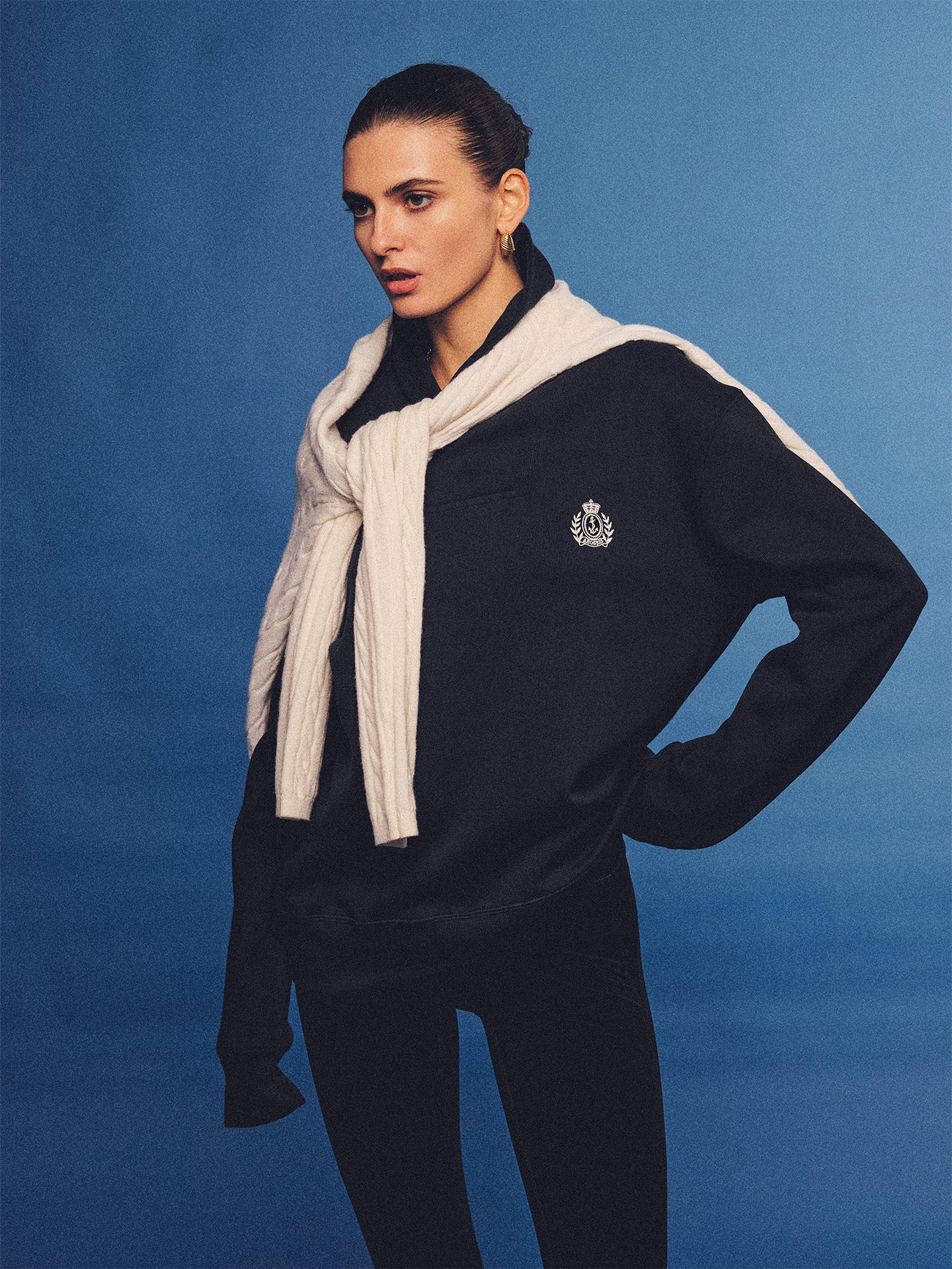 Arosris navy offshore crest shawl collar sweatshirt, styled with a tied sweater and retro sneakers for an effortless 90s vintage country club aesthetic.