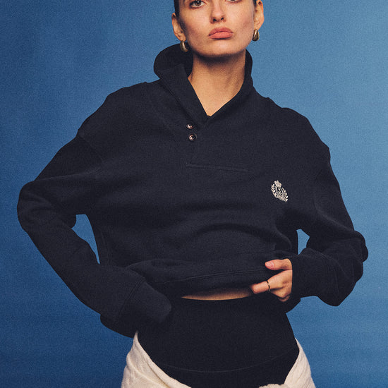 Arosris navy offshore crest shawl collar sweatshirt, styled with a tied sweater and retro sneakers for an effortless 90s vintage country club aesthetic.