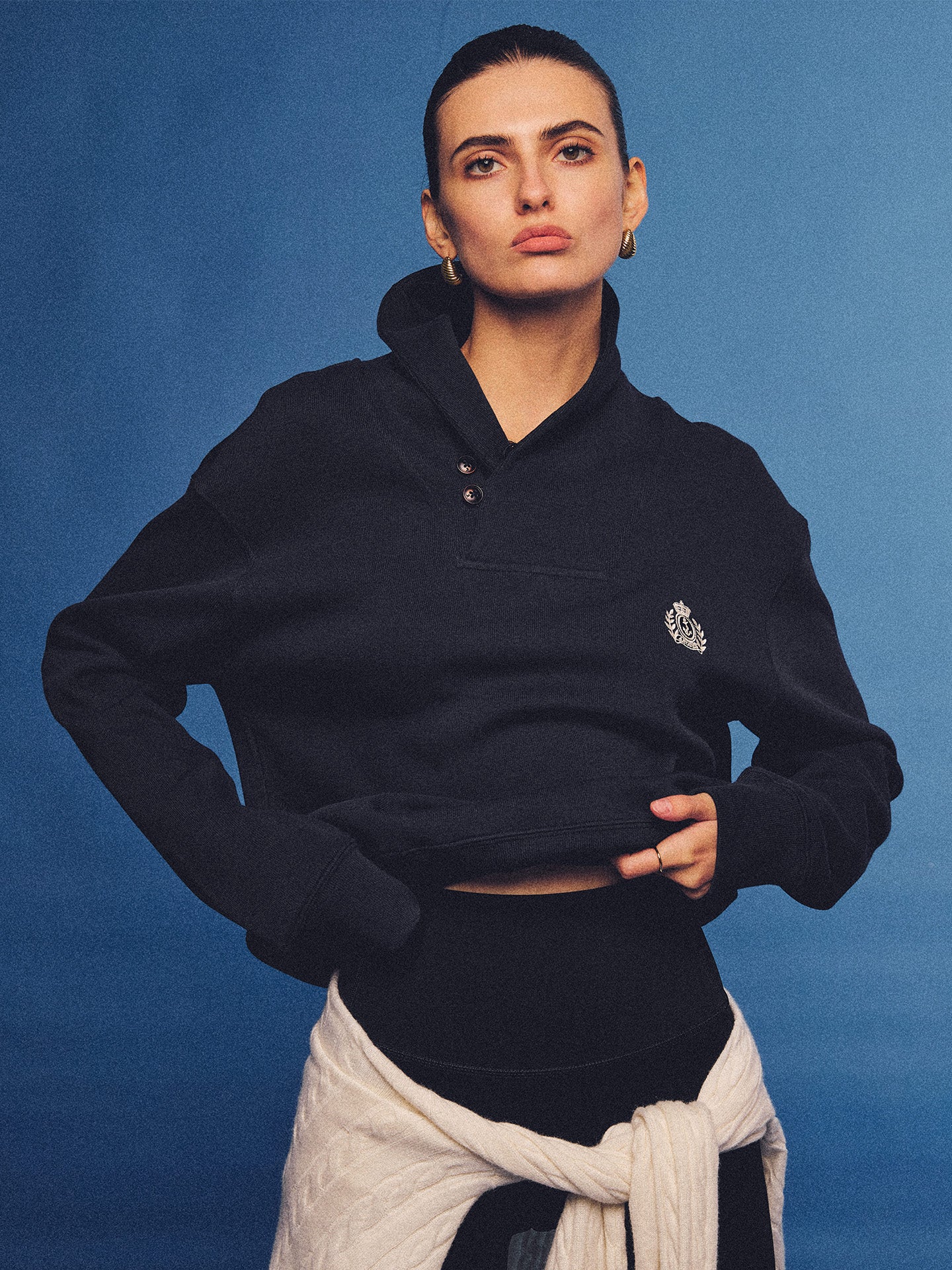 Arosris navy offshore crest shawl collar sweatshirt, styled with a tied sweater and retro sneakers for an effortless 90s vintage country club aesthetic.