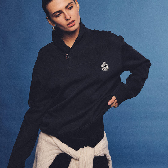 Arosris navy offshore crest shawl collar sweatshirt, styled with a tied sweater and retro sneakers for an effortless 90s vintage country club aesthetic.