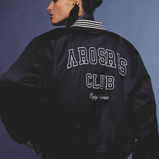 Arosris midnight navy high-gloss satin padded bomber jacket featuring a bold vintage club back embroidery, styled for an effortless 90s sporty-chic varsity aesthetic.