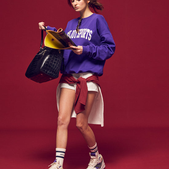 Arosris Ivy Archive Enjoy Sports crewneck sweatshirt in purple, styled with white shorts, sneakers, and a basketball for an effortless 90s off-duty street style look.