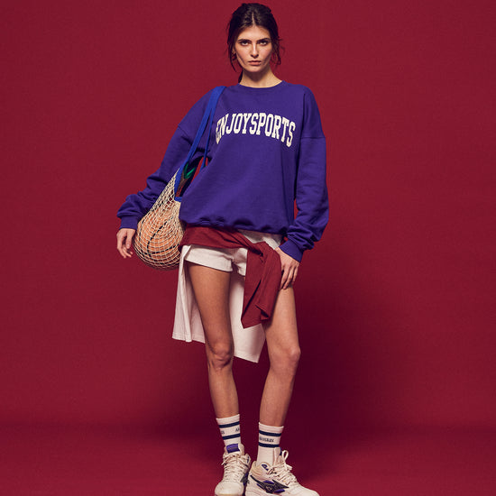 Arosris Ivy Archive Enjoy Sports crewneck sweatshirt in purple, styled with white shorts, sneakers, and a basketball for an effortless 90s off-duty street style look.