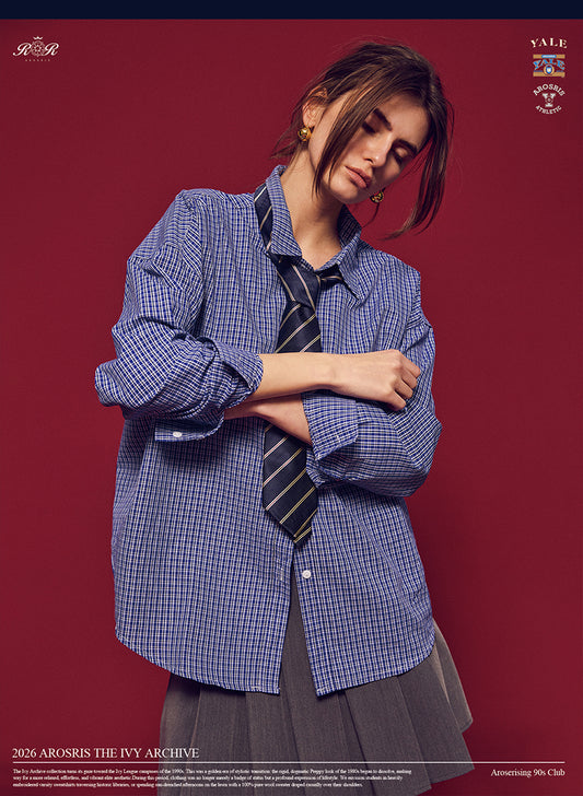 Arosris Ivy Archive oversized plaid shirt in blue, styled with a striped tie and grey pleated skirt for an effortless vintage 90s look.
