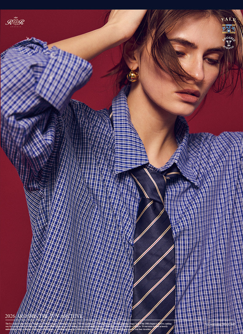Arosris Ivy Archive oversized plaid shirt in blue, styled with a striped tie and grey pleated skirt for an effortless vintage 90s look.