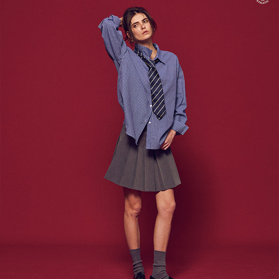 Arosris Ivy Archive oversized plaid shirt in blue, styled with a striped tie and grey pleated skirt for an effortless vintage 90s look.