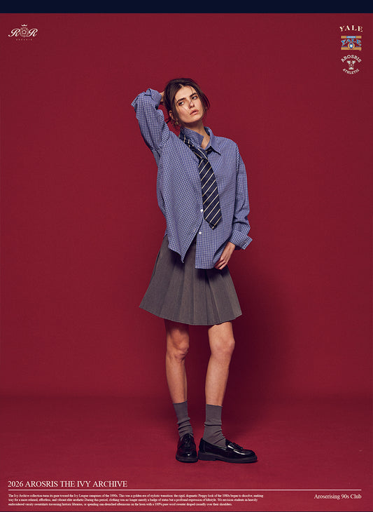 Arosris Ivy Archive oversized plaid shirt in blue, styled with a striped tie and grey pleated skirt for an effortless vintage 90s look.