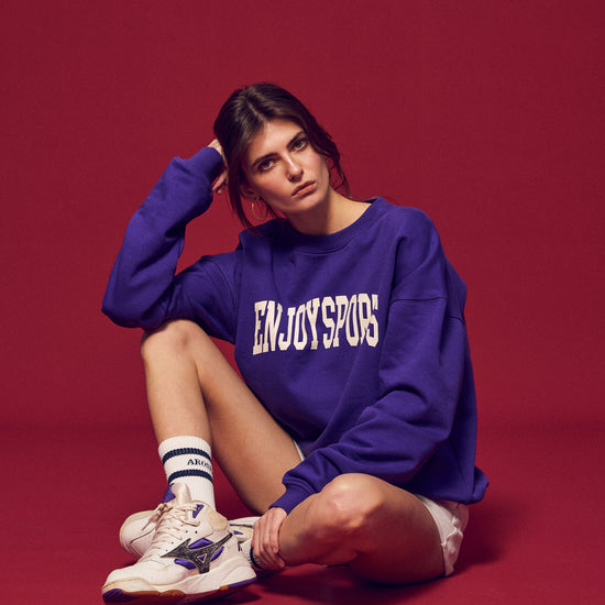 Arosris Ivy Archive Enjoy Sports crewneck sweatshirt in purple, styled with white shorts, sneakers, and a basketball for an effortless 90s off-duty street style look.