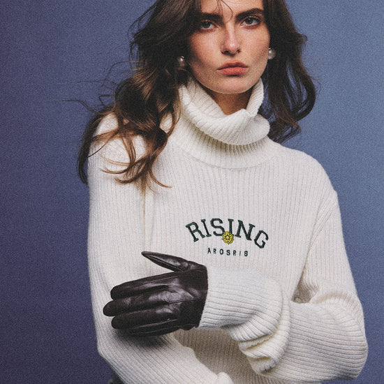 Arosris classic modern white ribbed wool blend turtleneck featuring a vintage 'RISING' floral embroidery, elegantly styled on a model as an effortless 90s preppy foundational layering piece.