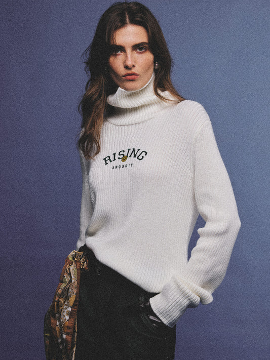 Arosris classic modern white ribbed wool blend turtleneck featuring a vintage 'RISING' floral embroidery, elegantly styled on a model as an effortless 90s preppy foundational layering piece.