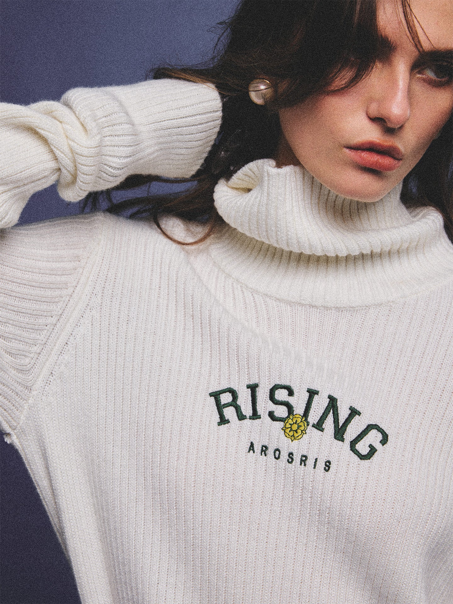 Arosris classic modern white ribbed wool blend turtleneck featuring a vintage 'RISING' floral embroidery, elegantly styled on a model as an effortless 90s preppy foundational layering piece.
