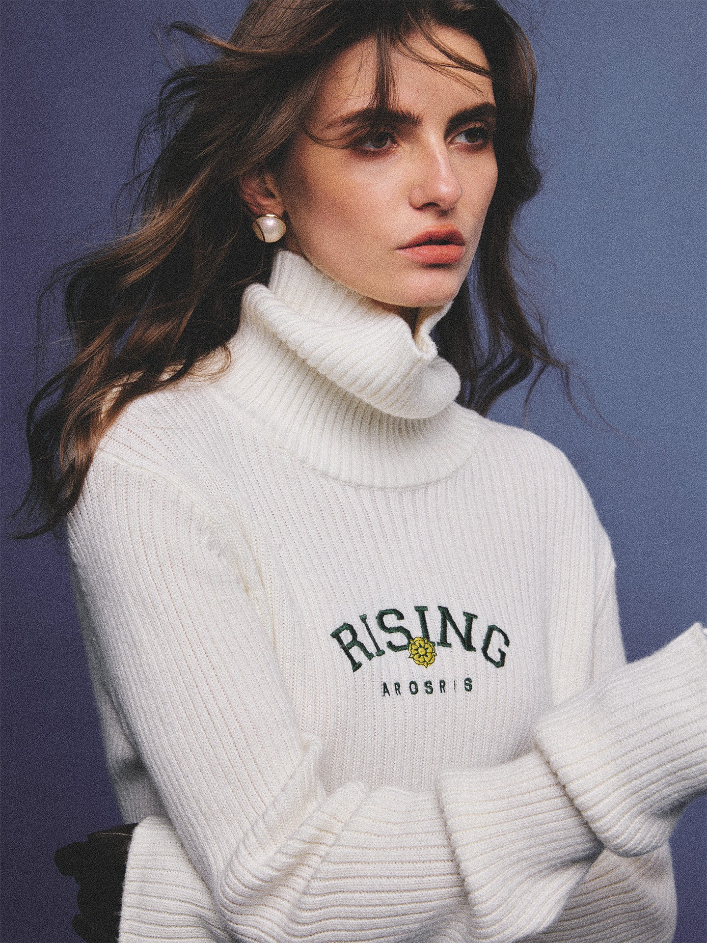 Arosris classic modern white ribbed wool blend turtleneck featuring a vintage 'RISING' floral embroidery, elegantly styled on a model as an effortless 90s preppy foundational layering piece.