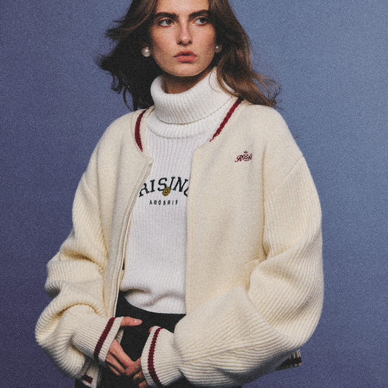 Arosris classic modern white ribbed wool blend turtleneck featuring a vintage 'RISING' floral embroidery, elegantly styled on a model as an effortless 90s preppy foundational layering piece.