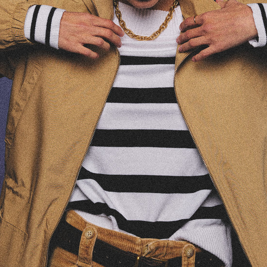 Arosris Riviera navy striped boat neck sweater elegantly styled on a model with corduroy shorts and vintage accessories, capturing an effortless 90s old money coastal resort aesthetic.