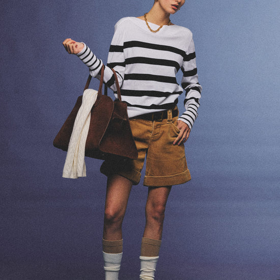 Arosris Riviera navy striped boat neck sweater elegantly styled on a model with corduroy shorts and vintage accessories, capturing an effortless 90s old money coastal resort aesthetic.