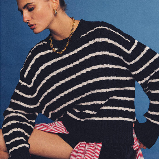 Arosris navy and white nautical striped crewneck sweater, styled with a contrast shirt tied at the waist for an effortless 90s vintage sporty-chic aesthetic.