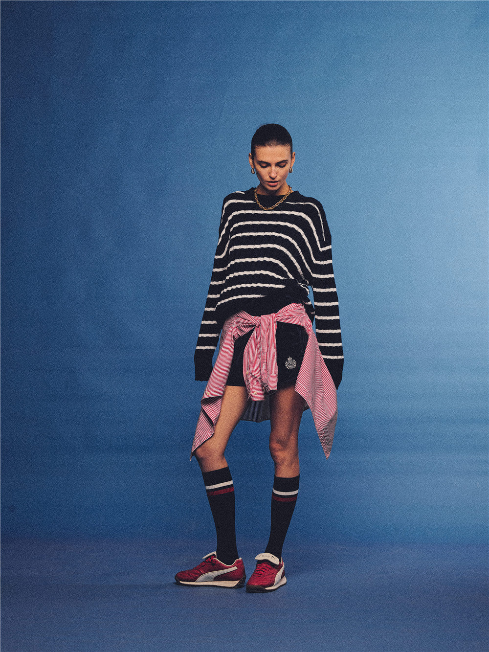 Arosris navy and white nautical striped crewneck sweater, styled with a contrast shirt tied at the waist for an effortless 90s vintage sporty-chic aesthetic.