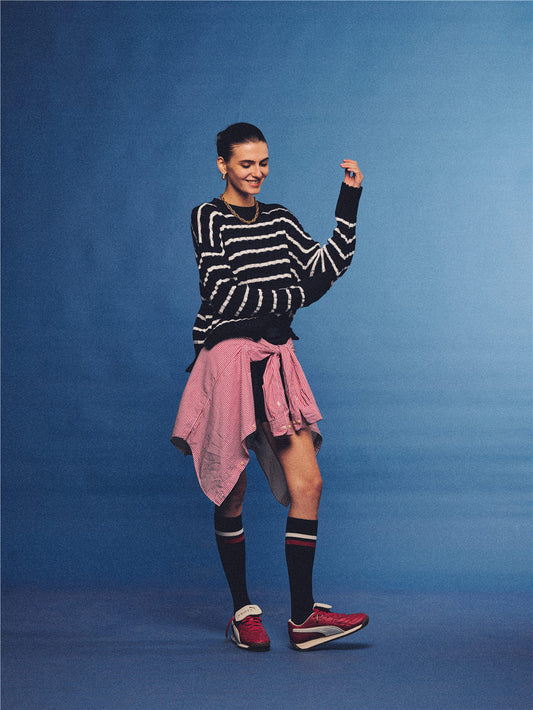 Arosris navy and white nautical striped crewneck sweater, styled with a contrast shirt tied at the waist for an effortless 90s vintage sporty-chic aesthetic.