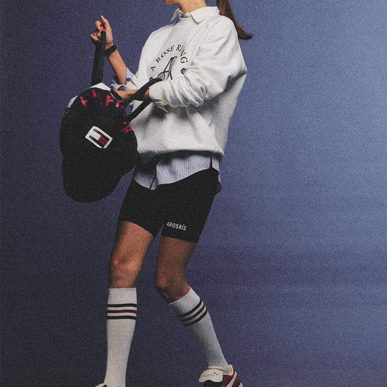 Arosris club white tennis club heritage sweatshirt with vintage crest graphic layered over a crisp collared shirt, elegantly styled on a model for an effortless 90s tenniscore and old money sporty rich aesthetic.