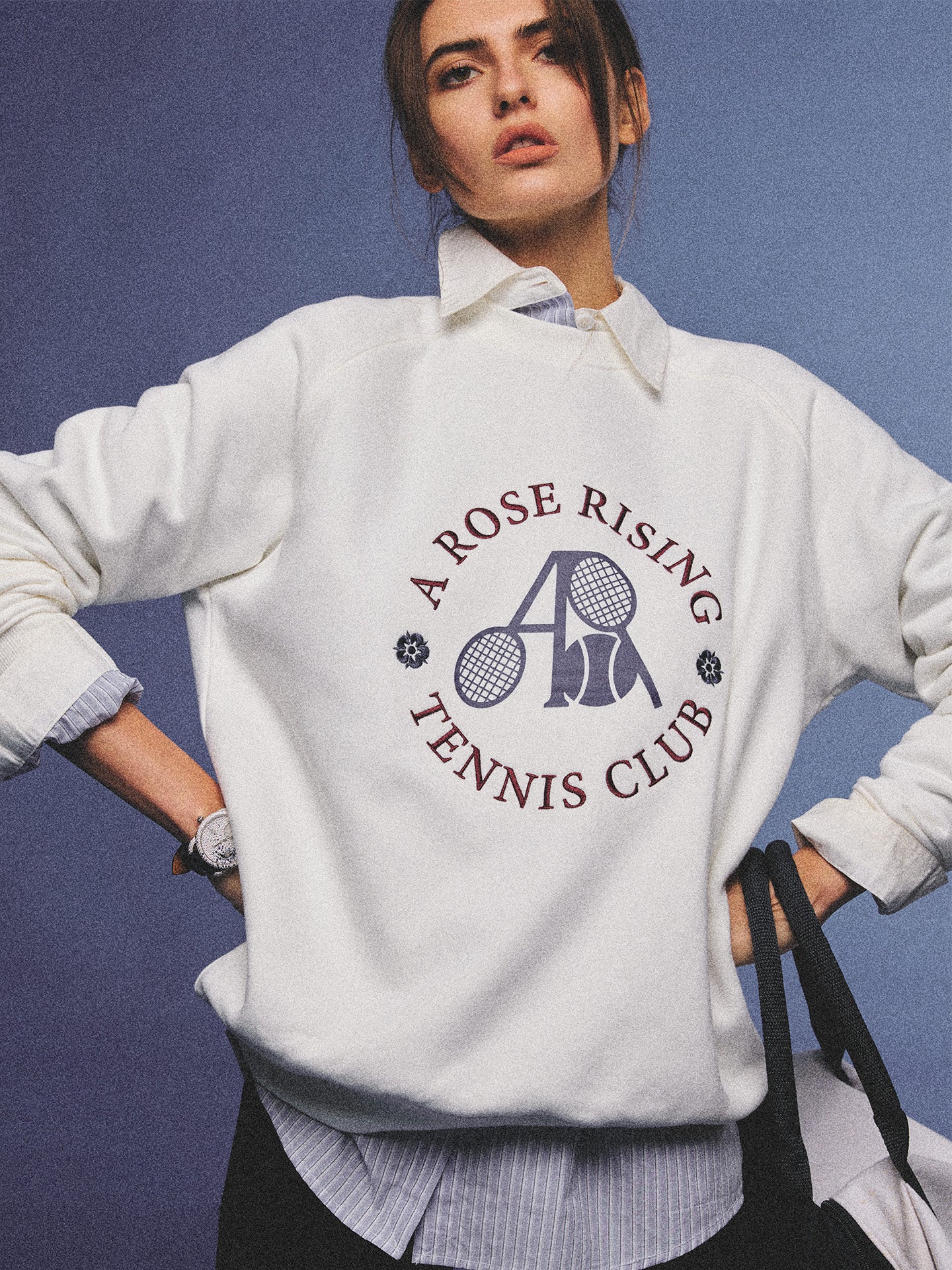 Arosris club white tennis club heritage sweatshirt with vintage crest graphic layered over a crisp collared shirt, elegantly styled on a model for an effortless 90s tenniscore and old money sporty rich aesthetic.