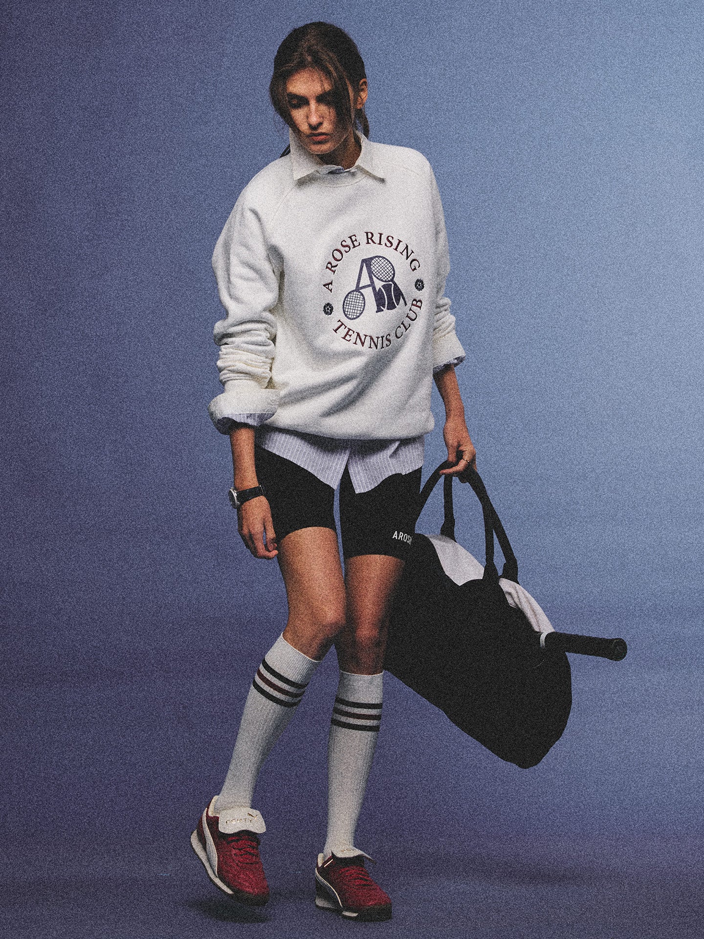 Arosris club white tennis club heritage sweatshirt with vintage crest graphic layered over a crisp collared shirt, elegantly styled on a model for an effortless 90s tenniscore and old money sporty rich aesthetic.