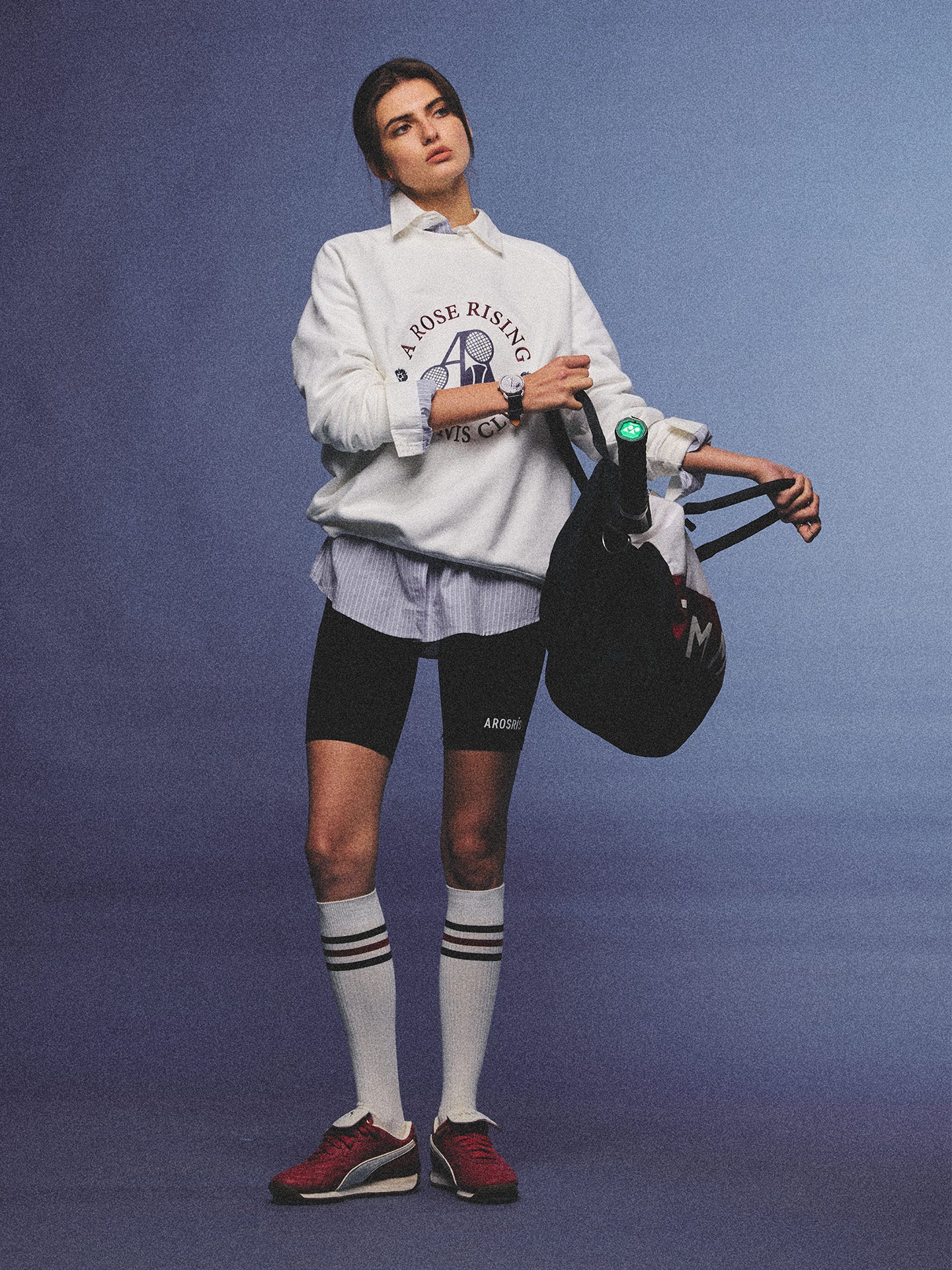 Arosris club white tennis club heritage sweatshirt with vintage crest graphic layered over a crisp collared shirt, elegantly styled on a model for an effortless 90s tenniscore and old money sporty rich aesthetic.