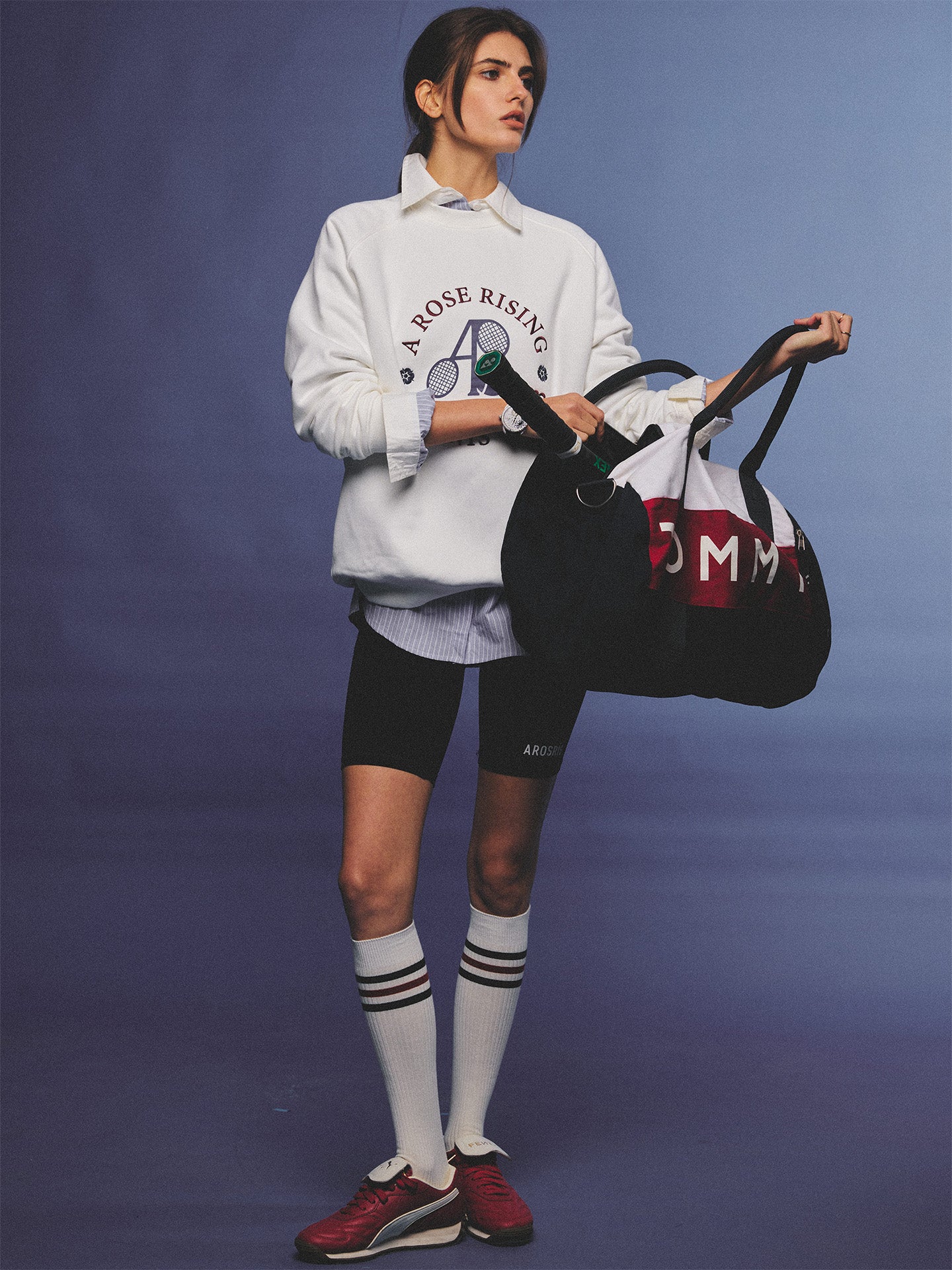 Arosris club white tennis club heritage sweatshirt with vintage crest graphic layered over a crisp collared shirt, elegantly styled on a model for an effortless 90s tenniscore and old money sporty rich aesthetic.