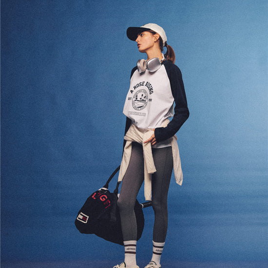 Arosris white and navy raglan long sleeve T-shirt, styled with a tennis skirt and cap for an effortless 90s vintage sporty-rich aesthetic.