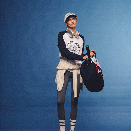 Arosris white and navy raglan long sleeve T-shirt, styled with a tennis skirt and cap for an effortless 90s vintage sporty-rich aesthetic.