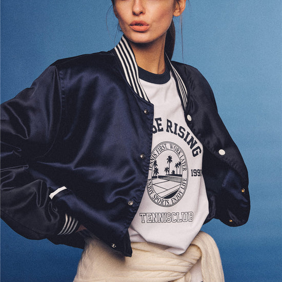 Arosris white and navy raglan long sleeve T-shirt, styled with a tennis skirt and cap for an effortless 90s vintage sporty-rich aesthetic.