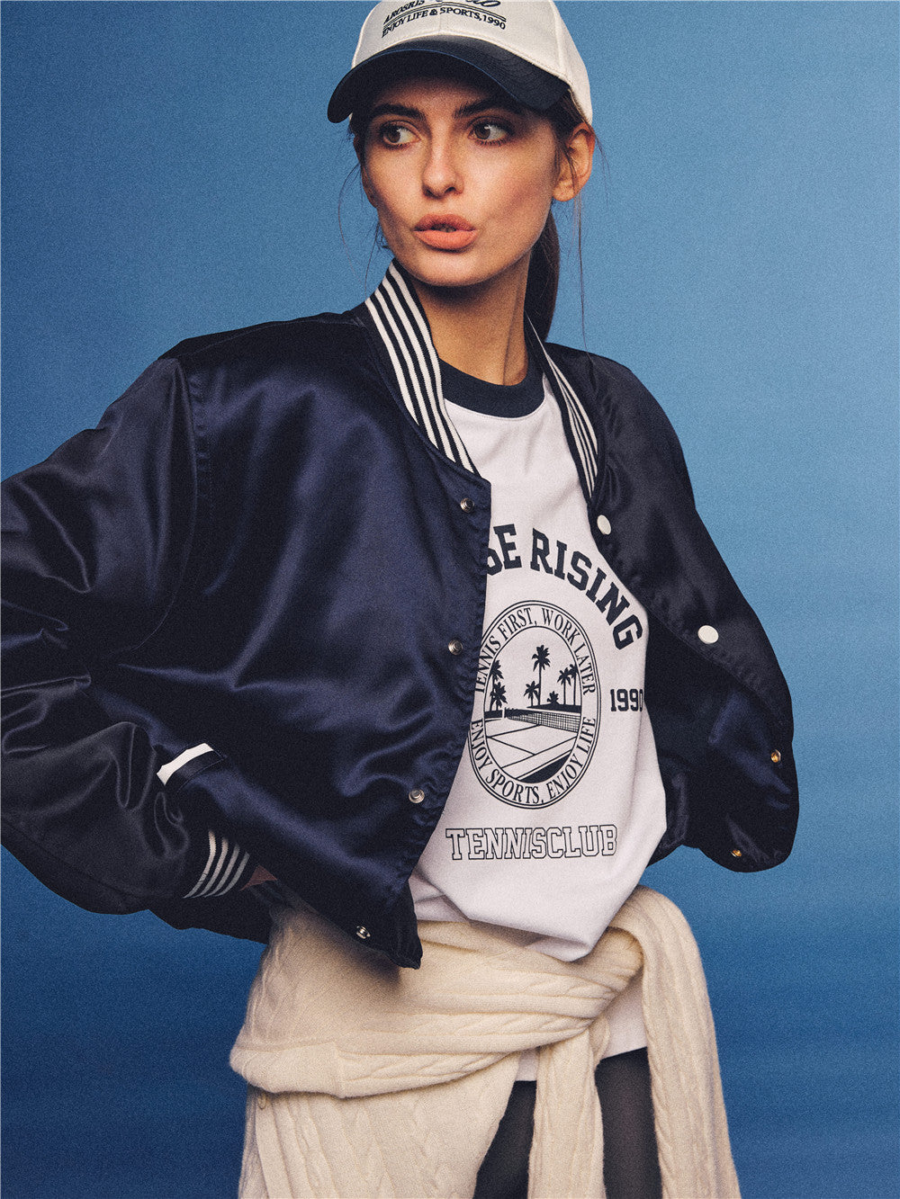 Arosris white and navy raglan long sleeve T-shirt, styled with a tennis skirt and cap for an effortless 90s vintage sporty-rich aesthetic.