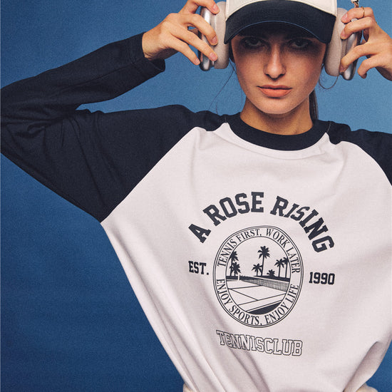 Arosris white and navy raglan long sleeve T-shirt, styled with a tennis skirt and cap for an effortless 90s vintage sporty-rich aesthetic.