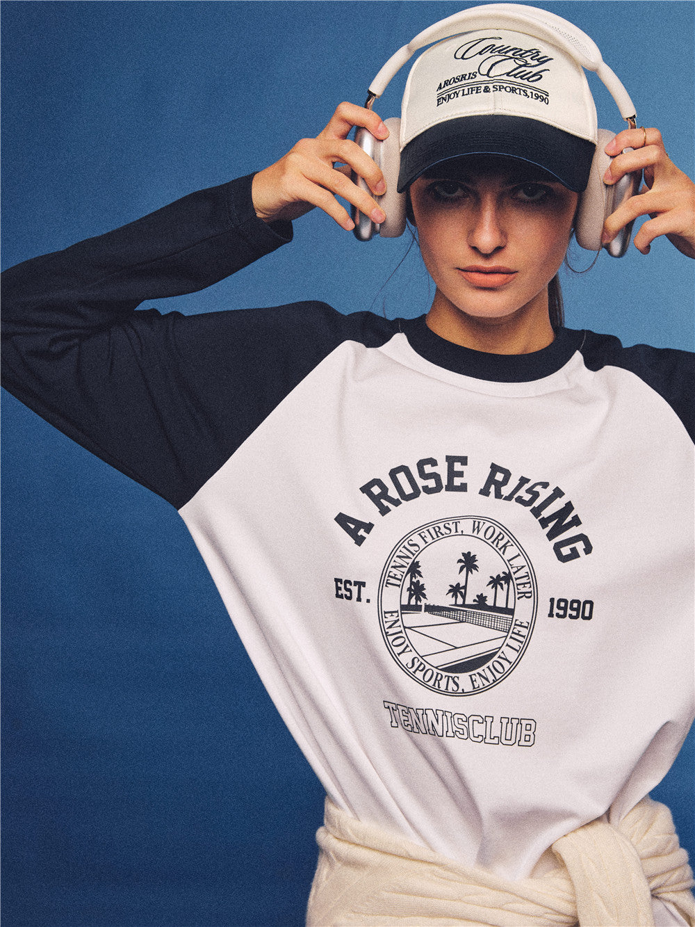 Arosris white and navy raglan long sleeve T-shirt, styled with a tennis skirt and cap for an effortless 90s vintage sporty-rich aesthetic.