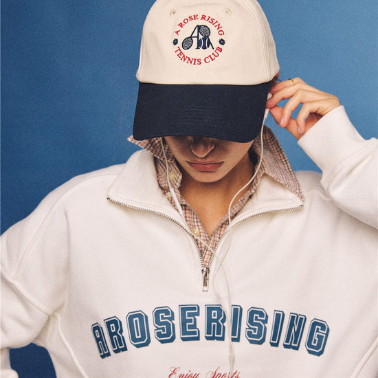 Arosris vintage-inspired two-tone cream and navy tennis club dad hat, styled with a retro half-zip sweatshirt for an effortless 90s sporty-rich aesthetic.